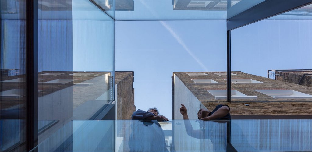 View from below of two men talking below a frameless glass roof
