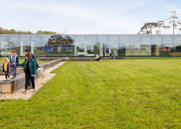 Frameless glass façade on a building in a field with a family in the foreground