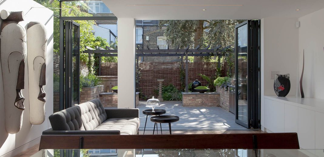 Modern, minimal living room with bi-fold garden doors and a frameless side return extension