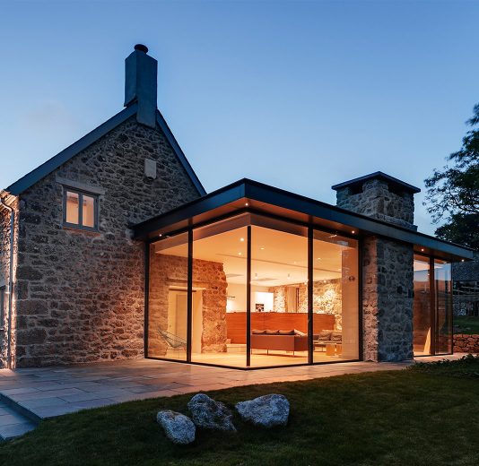 Rural stone house with modern frameless glass extension