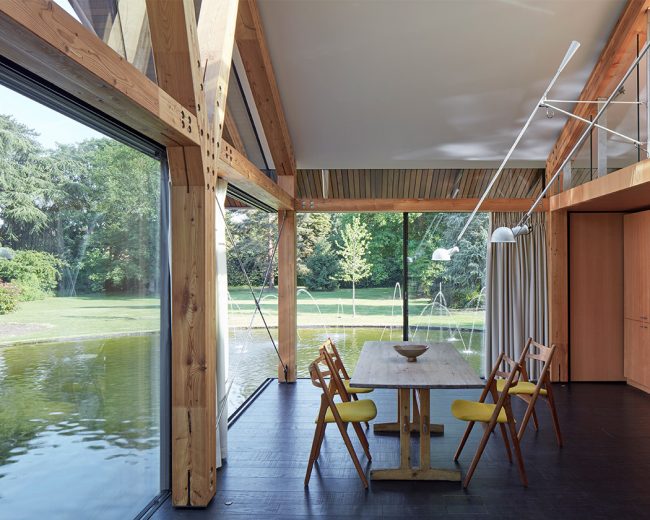 Dining room with frameless Sky-Frame doors sitting above a lake