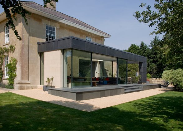 Limestone brick country house with a large glazed enclosure incorporating Sky-Frame minimally-framed doors