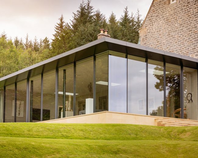 Glazed box extension on a country house featuring invisible corner glazing, fixed frameless glass and Sky-Frame sliding doors