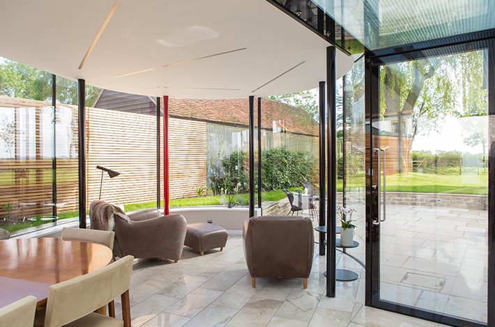 Garden room with curved, frameless glass walls and a PureGlaze pivot door
