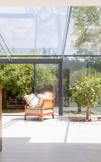 Fully glazed sun room with a small tree set into the stone floor